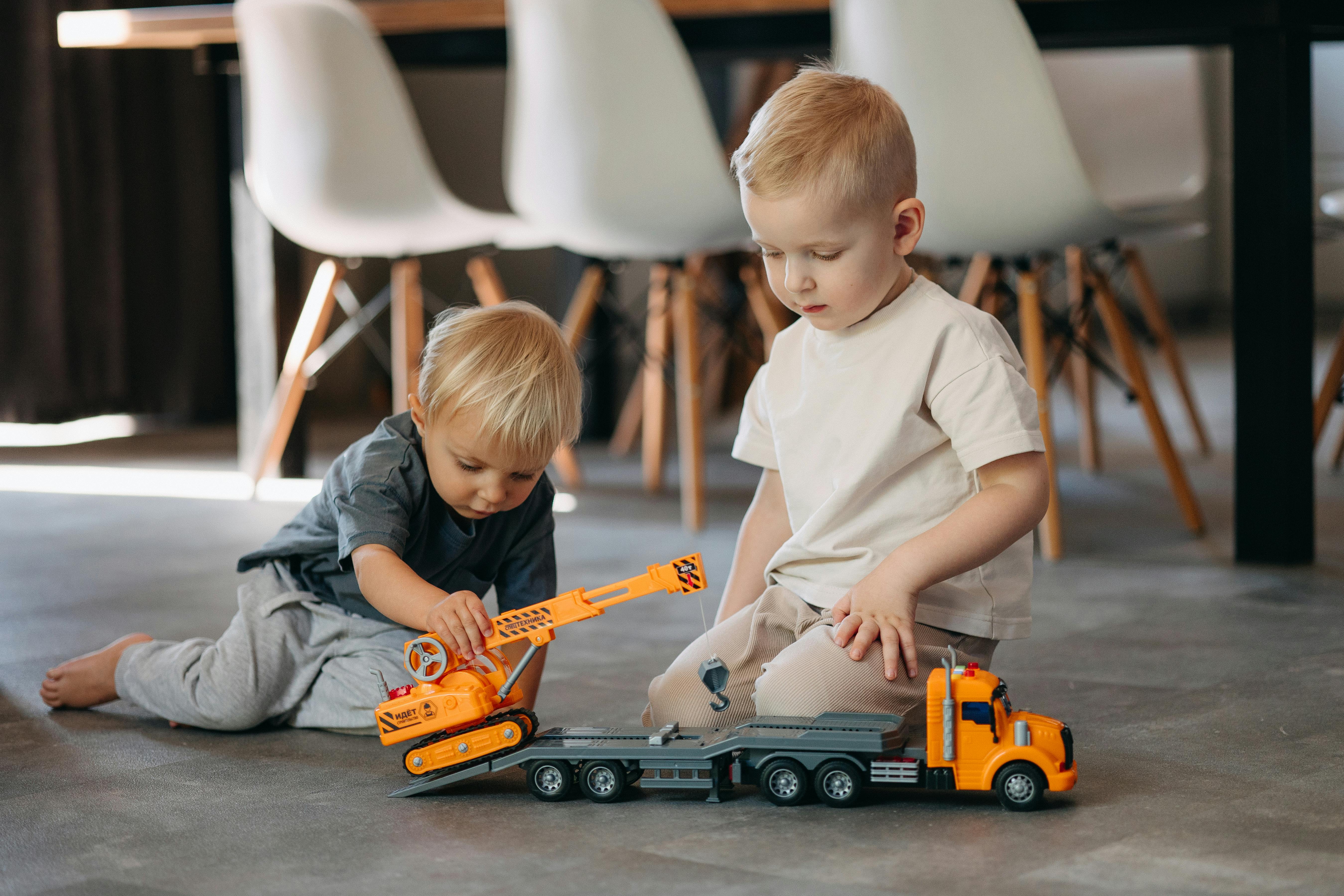 two children playing with toy trucks on the floor