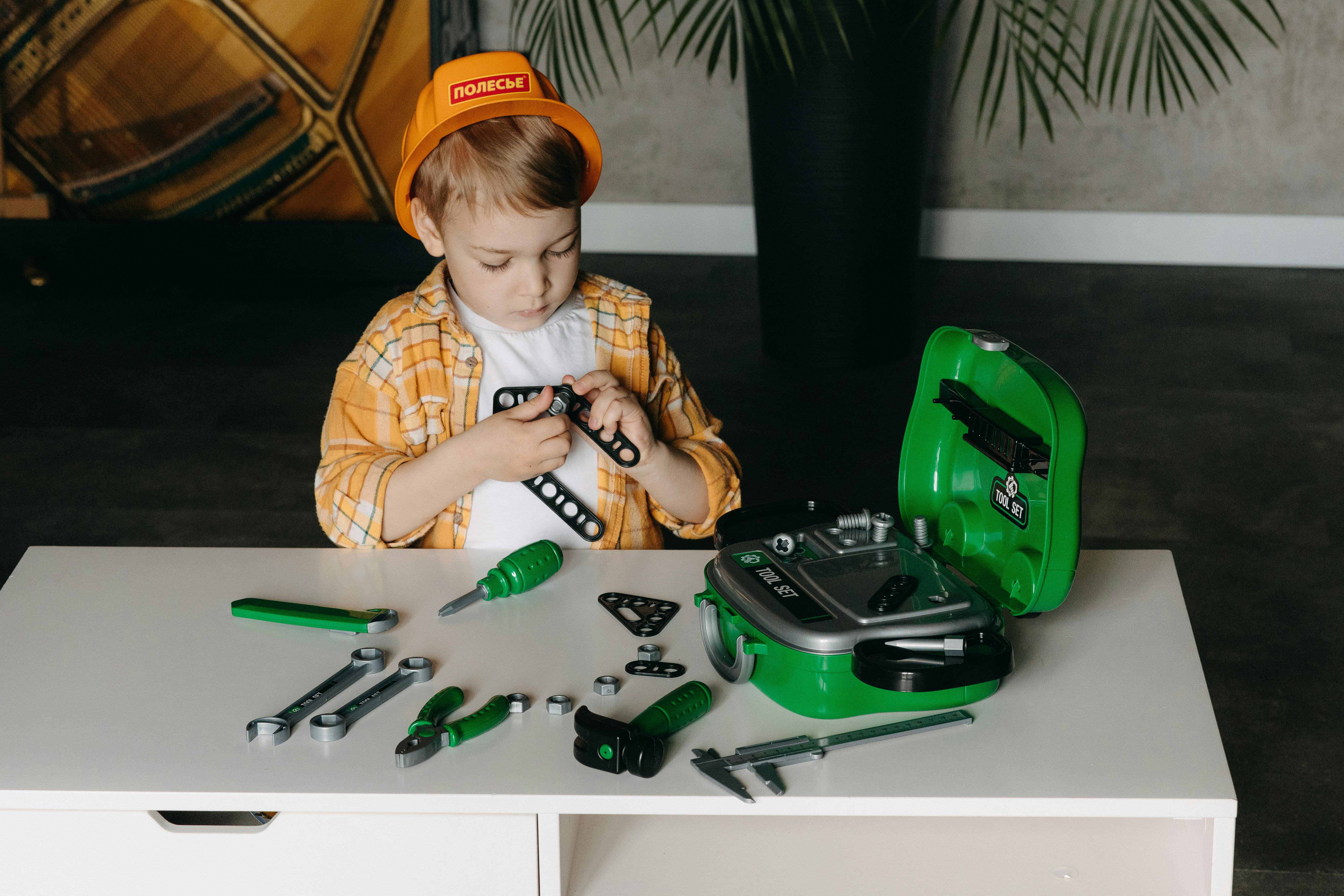 a young boy is working on a green toolbox