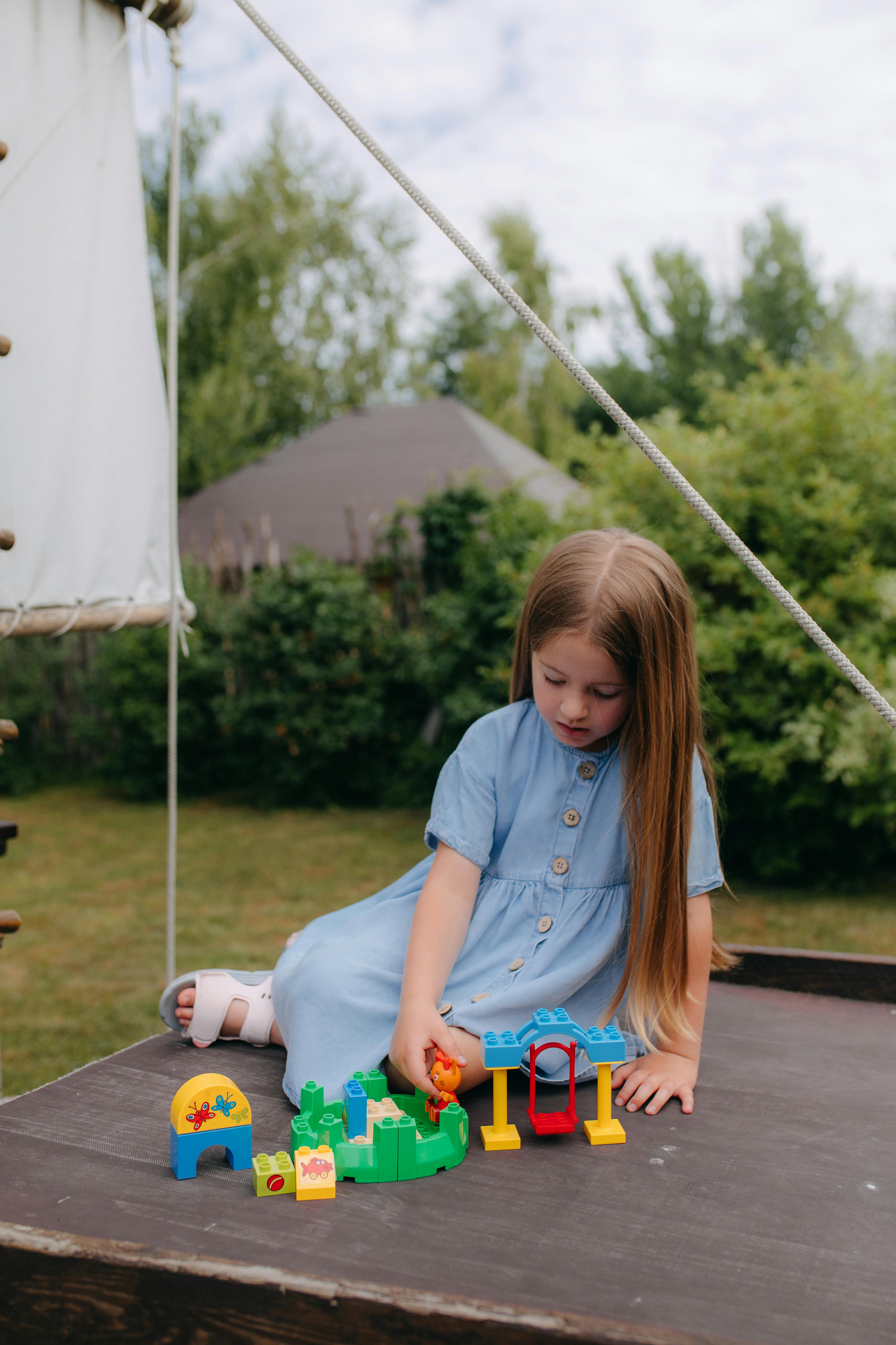 a little girl playing with toys on a wooden table