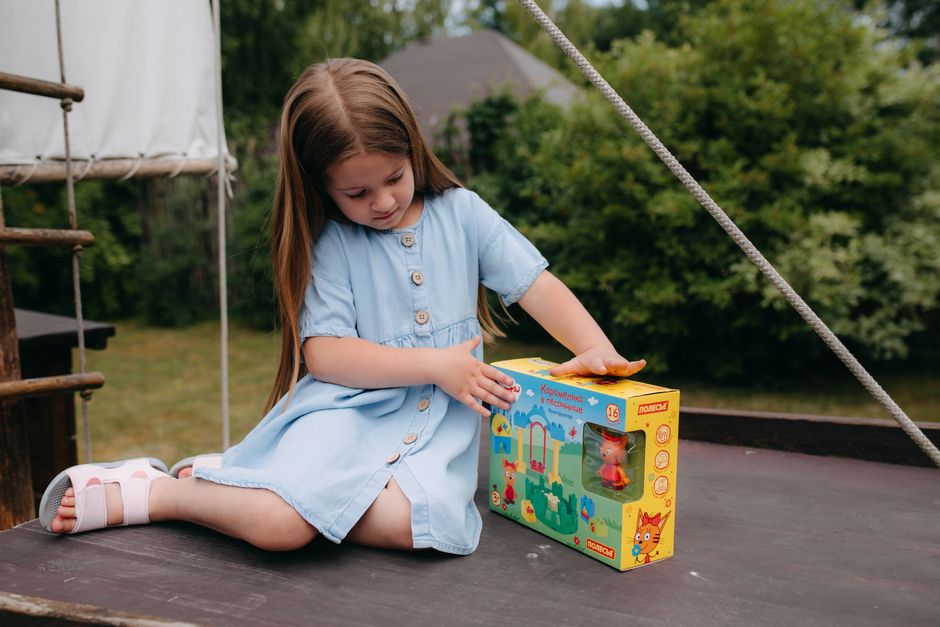 Photo by Polesie Toys on Pexels A girl enjoys a sunny day outdoors, playing with a colorful toy on a wooden structure. - Photo by Polesie Toys on Pexels
