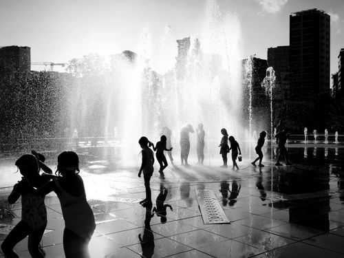 Free Silhouettes of children playing around a fountain in Istanbul city, captured in black and white. Stock Photo