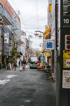 Bustling street scene in Tokyo showing people, vehicles, and shops.