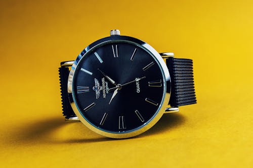Круглые аналоговые часы серебристого цвета с черным ремешком