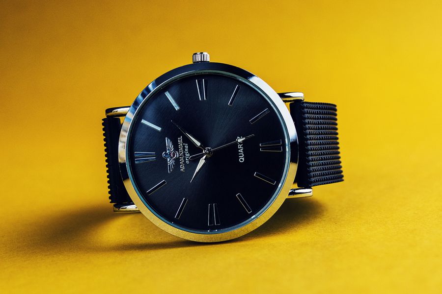 A minimalist watch resting on a warm ochre surface