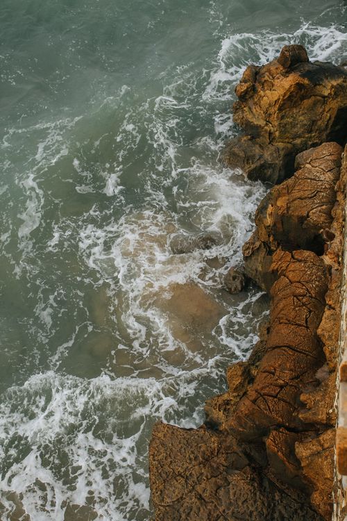 Free Aerial view of ocean waves crashing against rugged rocks in Asilah, Morocco, showcasing a dramatic seascape. Stock Photo