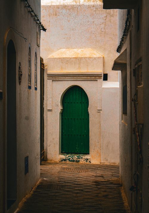 Free Capture of an ancient alleyway featuring a vibrant green door, showcasing Moroccan architecture. Stock Photo