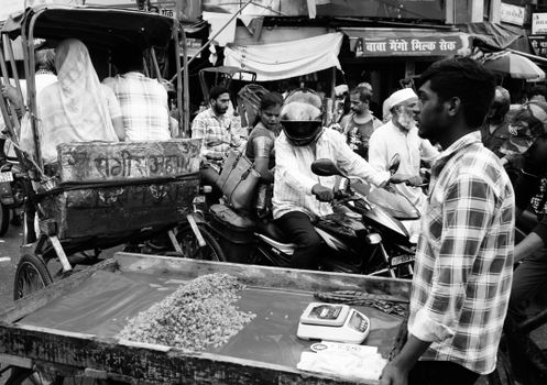 Black and white image of a bustling street market in Varanasi, India, showcasing diverse activities.