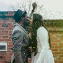 一对夫妇在户外五彩纸屑中亲吻，庆祝他们的婚礼