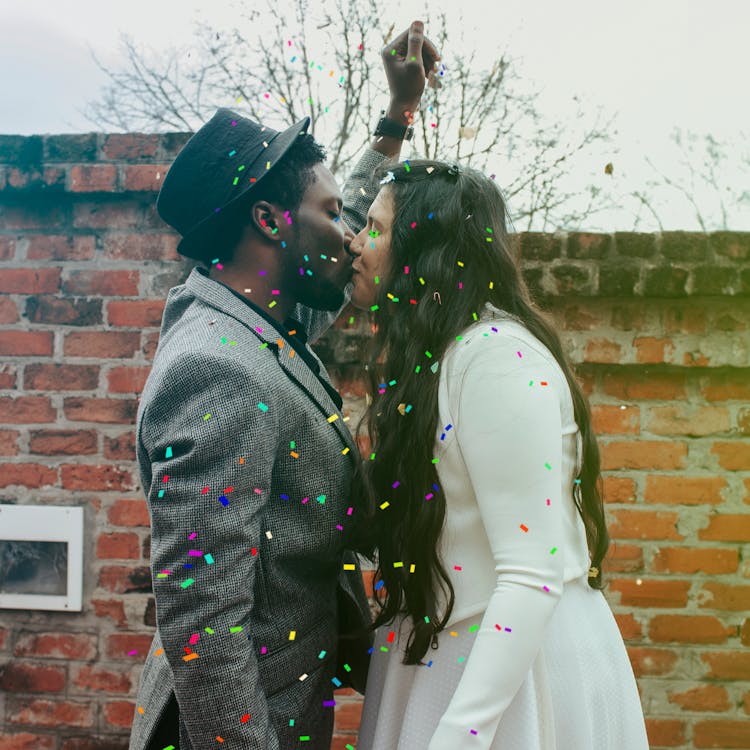 Man In Hat Kissing Woman In White Dress