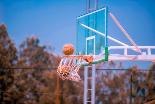 Basketball shot caught mid-air against a clear blue sky on an outdoor court.