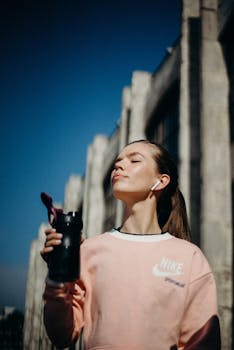 一名年轻女子在城市中拿着水瓶，享受阳光