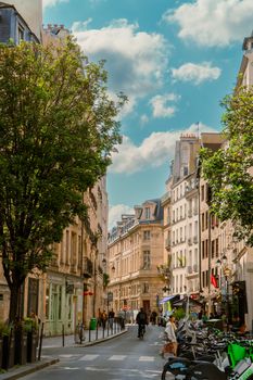 A vibrant street scene in Paris with historic buildings and people enjoying the spring weather.