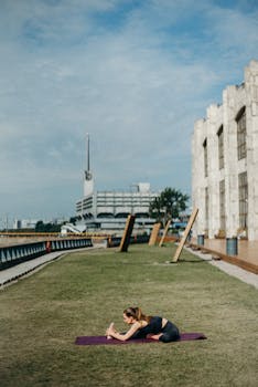 一名女子在城市公园的垫子上做瑜伽伸展，以促进健身和放松