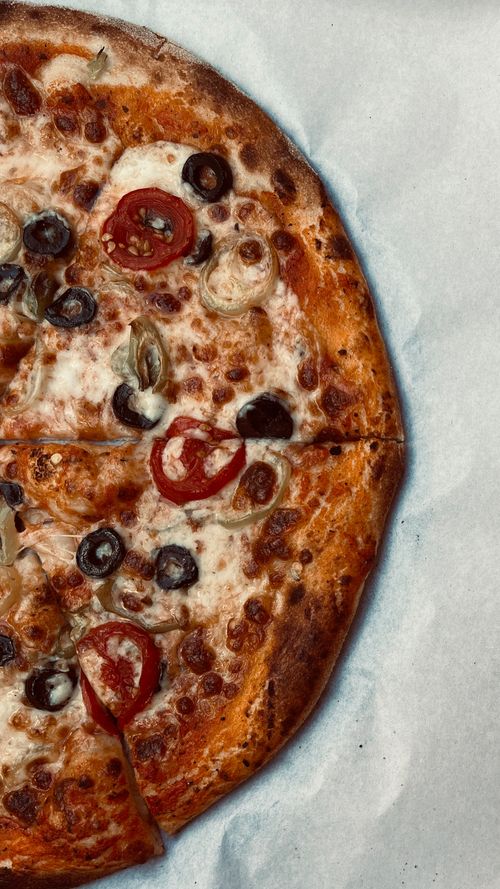 Free Tasty pizza topped with cheese, tomatoes, and olives, perfect for a meal. Stock Photo
