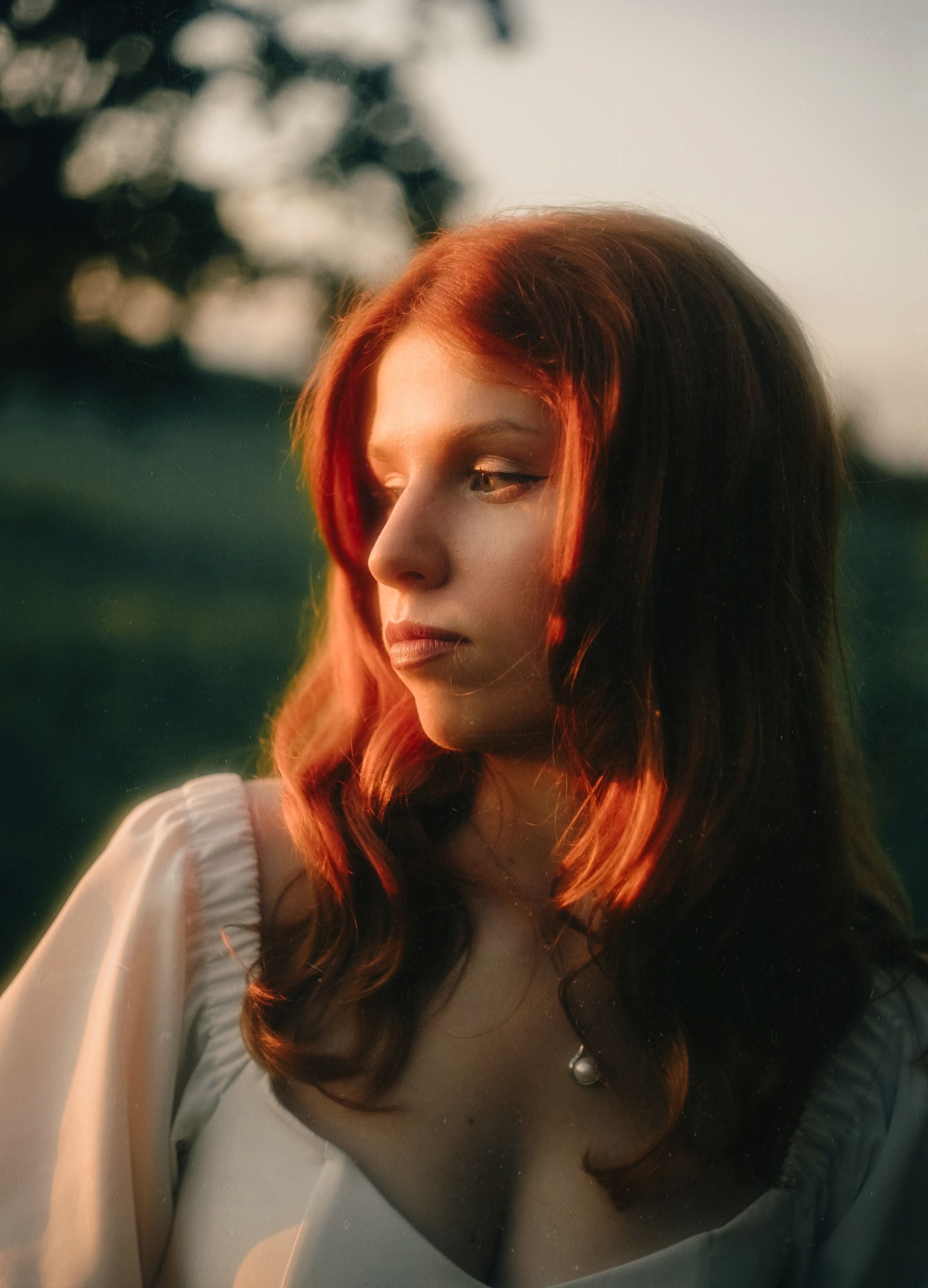 A thoughtful woman with red hair captured in warm, dreamy sunset lighting outdoors.. pexels, thoughtful, woman