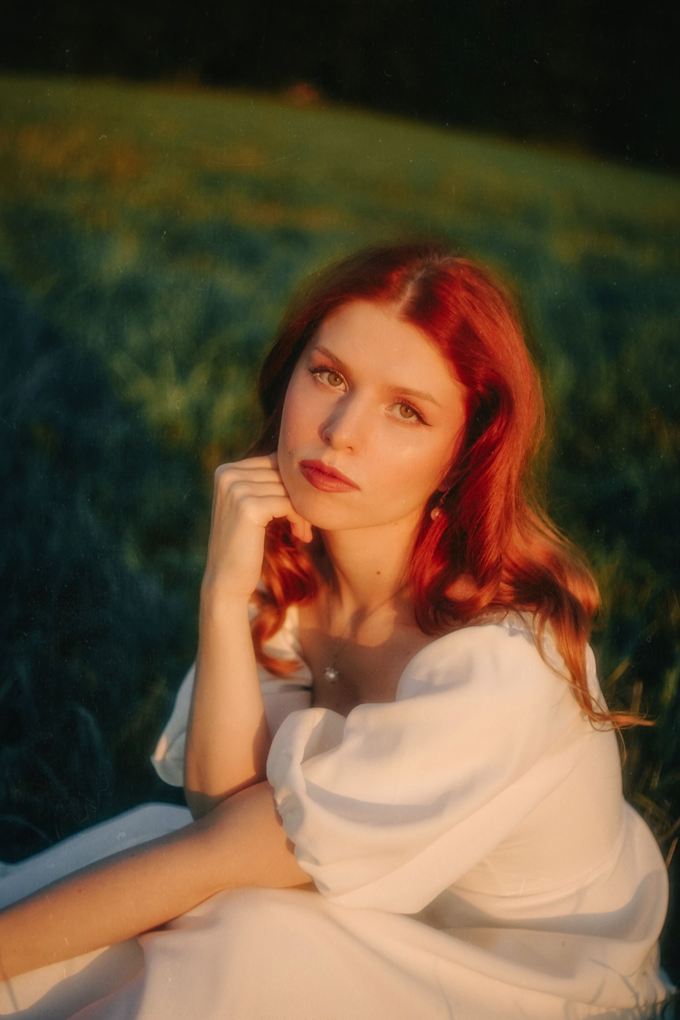A woman with red hair sitting in a field · Free Stock Photo