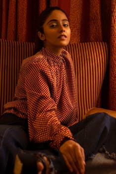 优雅的女人在室内穿着圆点上衣摆姿势，展示风格与优雅