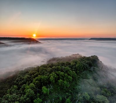 Breathtaking aerial view of a sunrise over fog-covered hills in Weaver Valley, showcasing lush greenery.