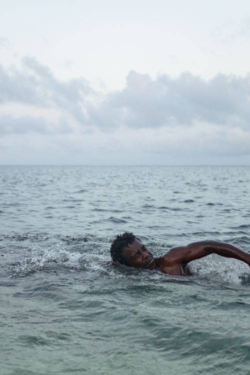 Free A man swimming in the ocean at Mombasa, Kenya, showcasing relaxation and outdoor leisure. Stock Photo