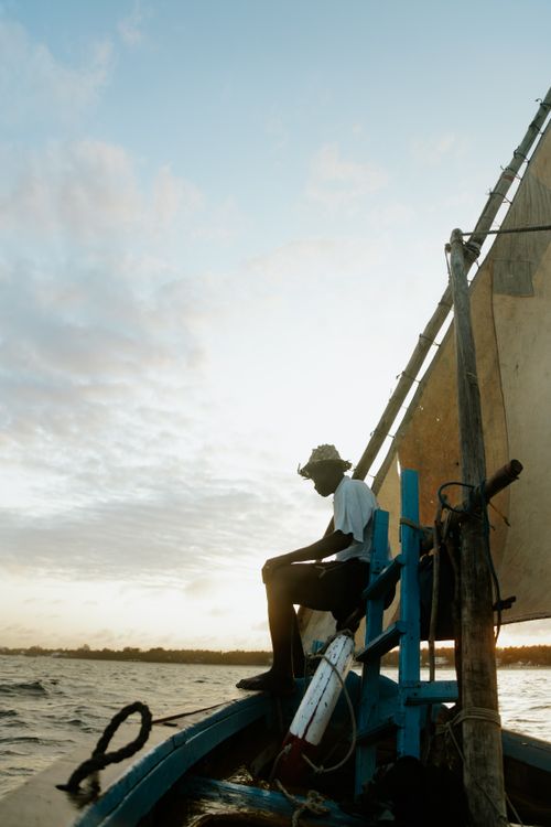 Free A serene scene of a fisherman sailing on a traditional boat at sunset in Mombasa, Kenya. Stock Photo