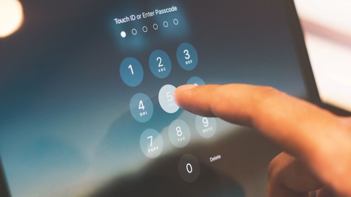 Dedo digitando um código de acesso na tela de segurança de um smartphone