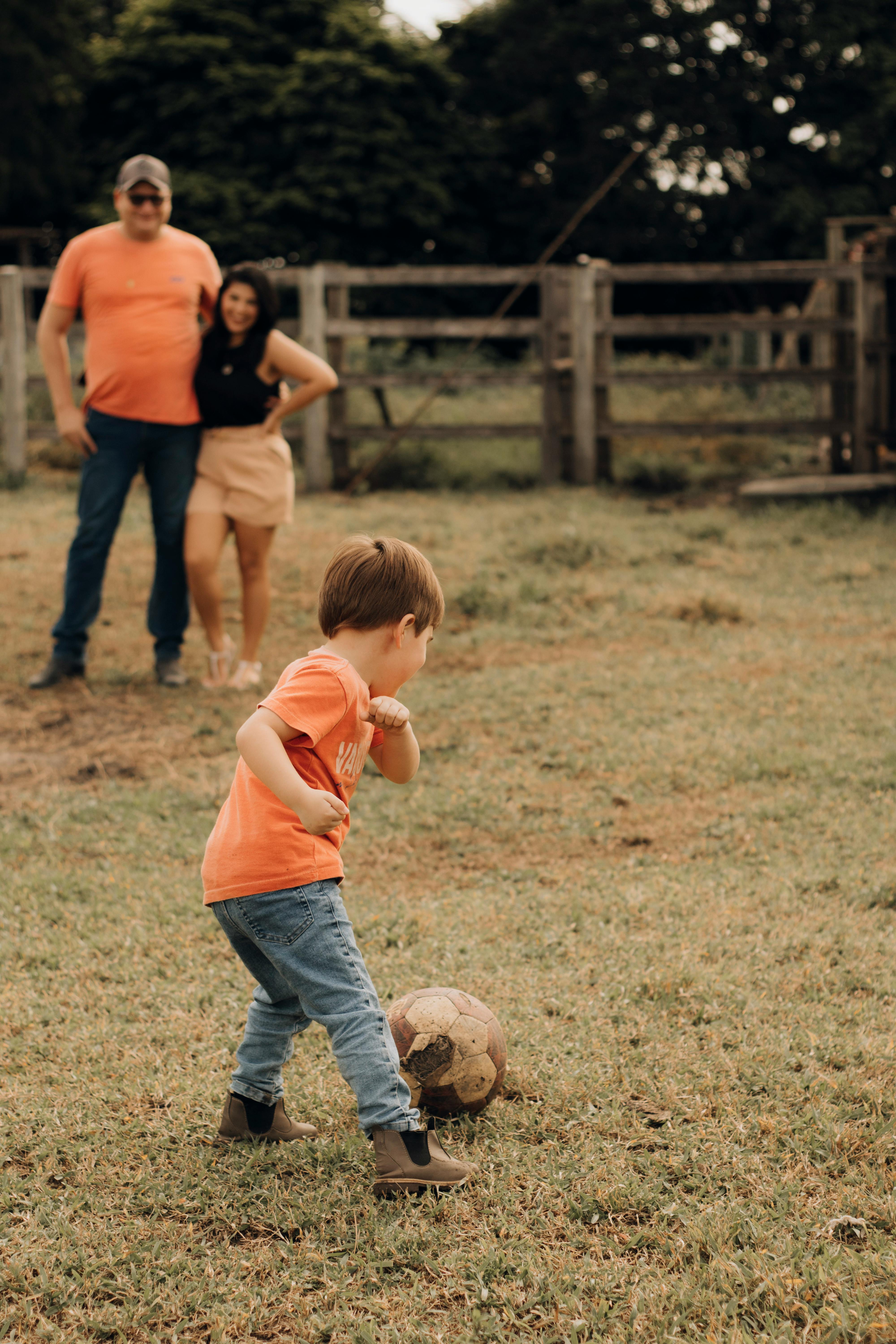 parent watching boy playing with ball