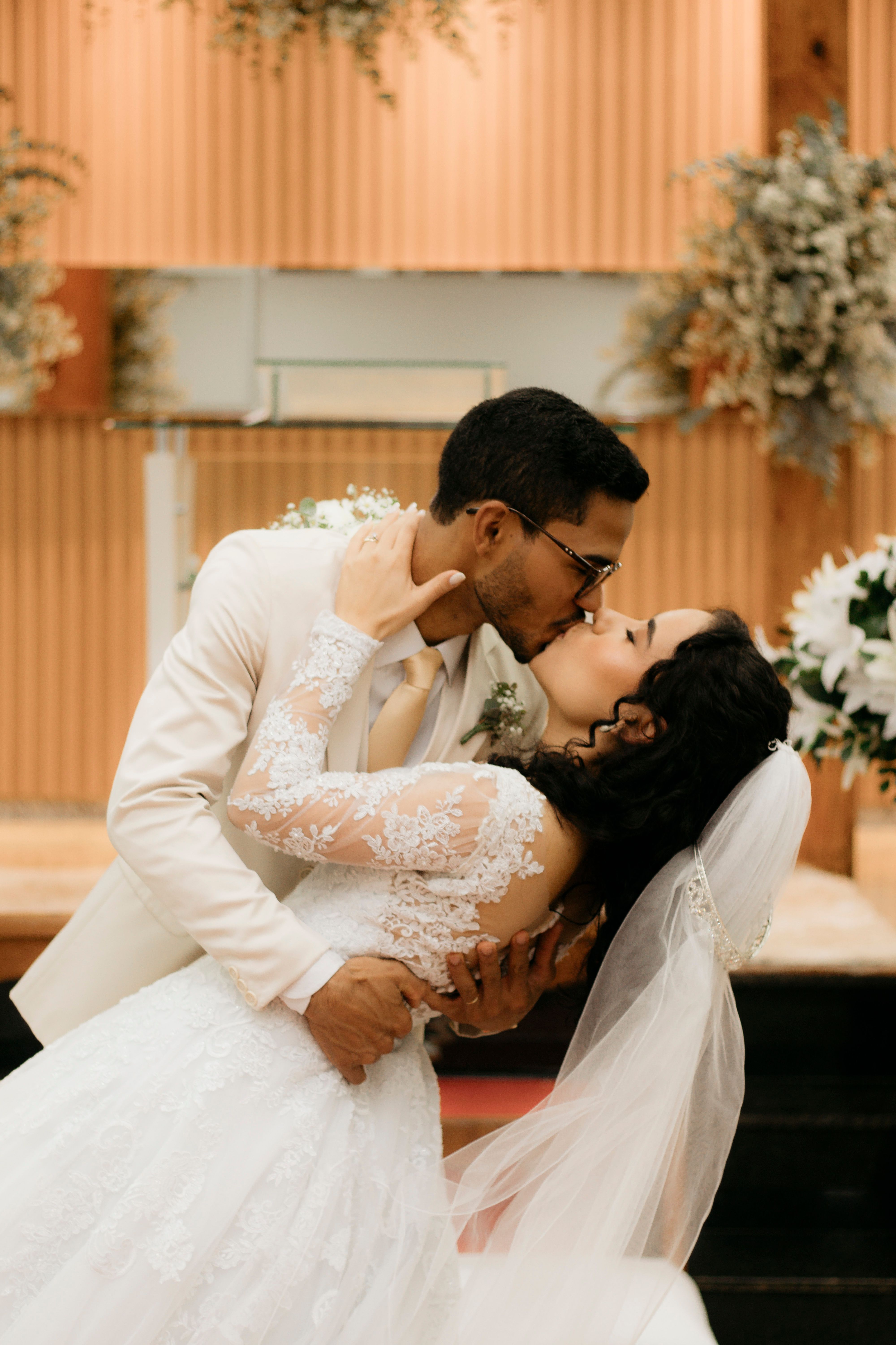 A bride and groom kiss in front of a church · Free Stock Photo