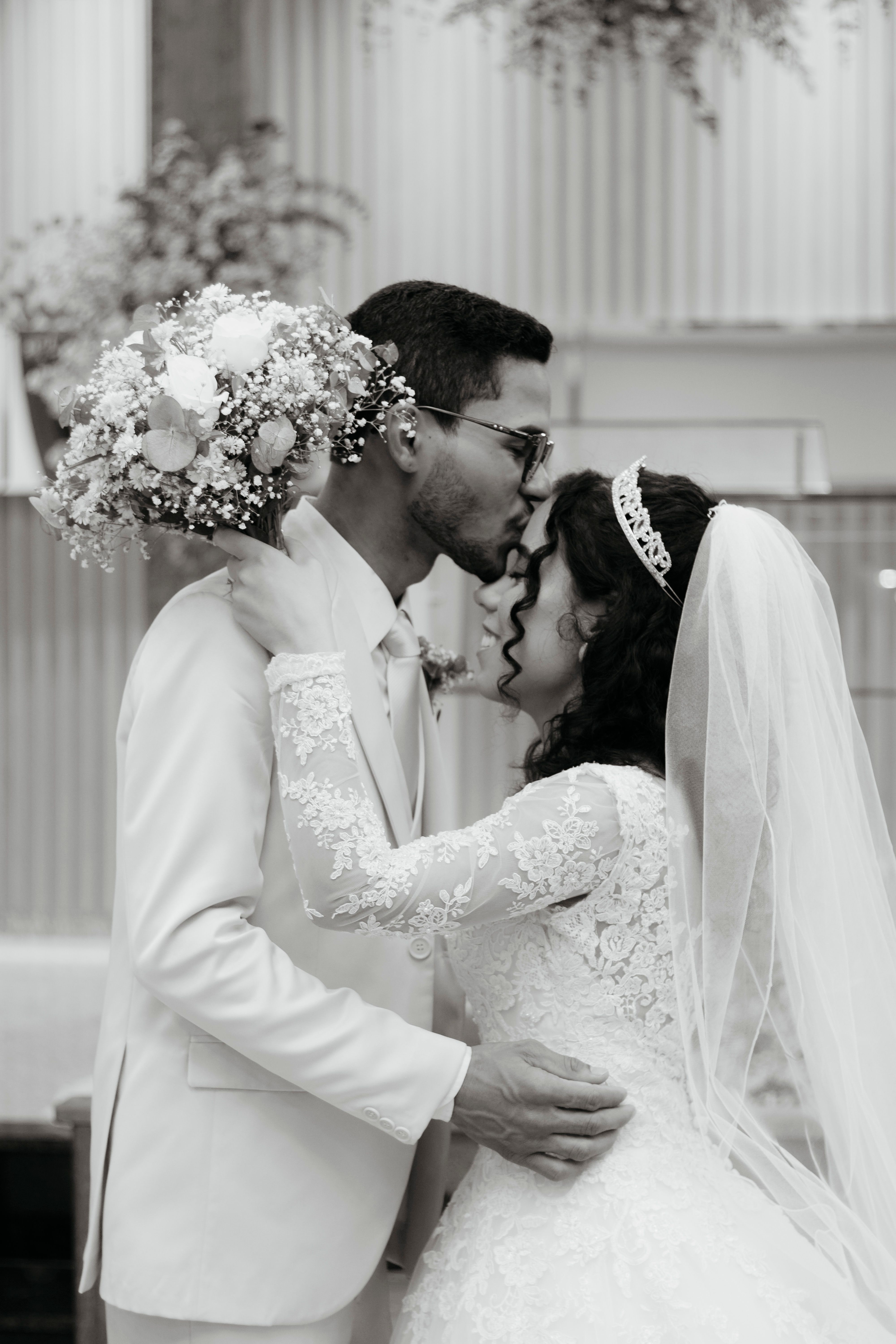 A bride and groom kiss in front of a church · Free Stock Photo