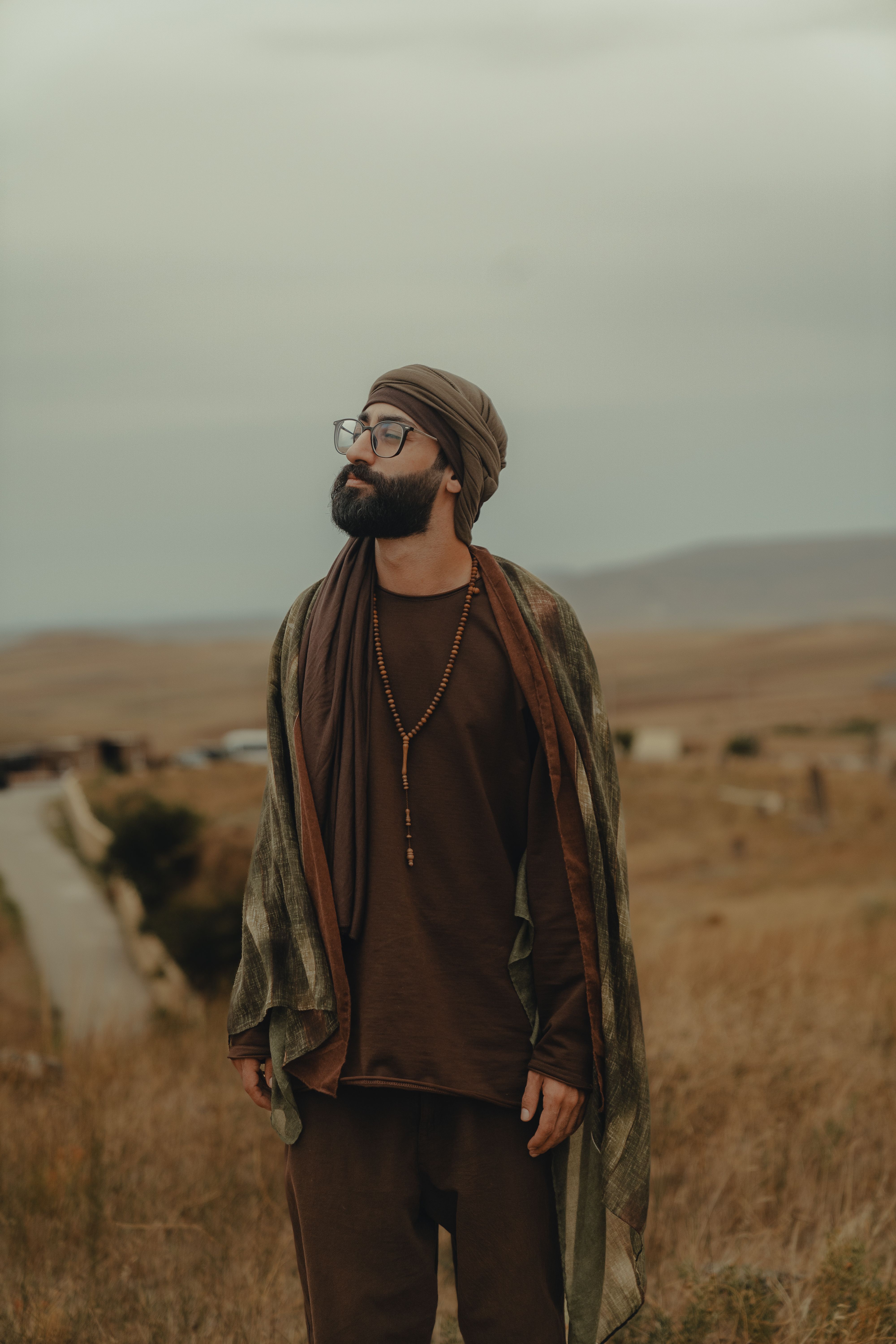 Bearded man with eyeglasses and turban enjoying leisure time in a countryside setting.