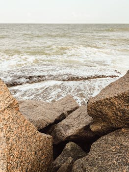 Peaceful view of ocean waves breaking on a rocky shore during sunset.