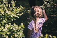 一个年轻的女孩编着头发，在郁郁葱葱的花园里享受阳光明媚的户外时光