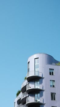 A contemporary London apartment building with curved balconies against a clear blue sky.