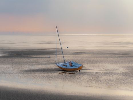 A tranquil scene of a boat resting on the sandy shore at West Kirby during a calm sunset, perfect for travel inspiration.