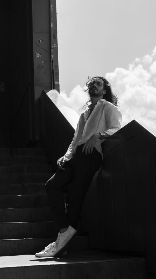 Free Stylish man poses on steps in dramatic black and white urban setting. Stock Photo