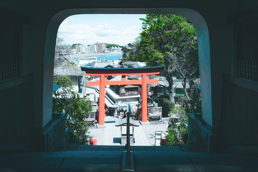 A picturesque scene featuring a Torii gate with cityscape and greenery in the background.
