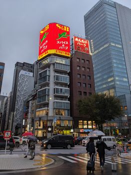 Bustling street in Tokyo with skyscrapers, cars, and neon signs at dusk.
