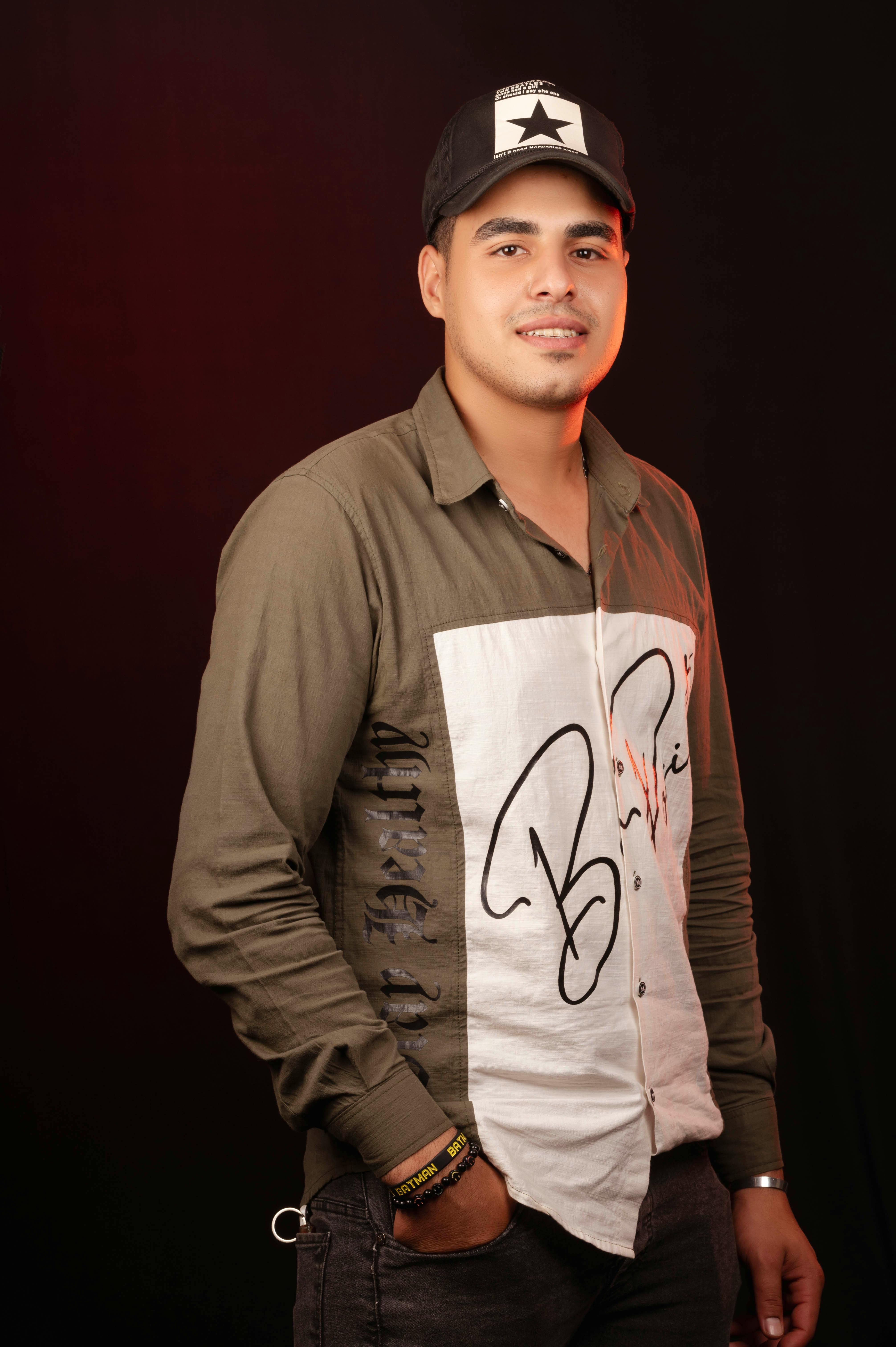 Young man in casual fashion posing with confident attitude against a dark background.