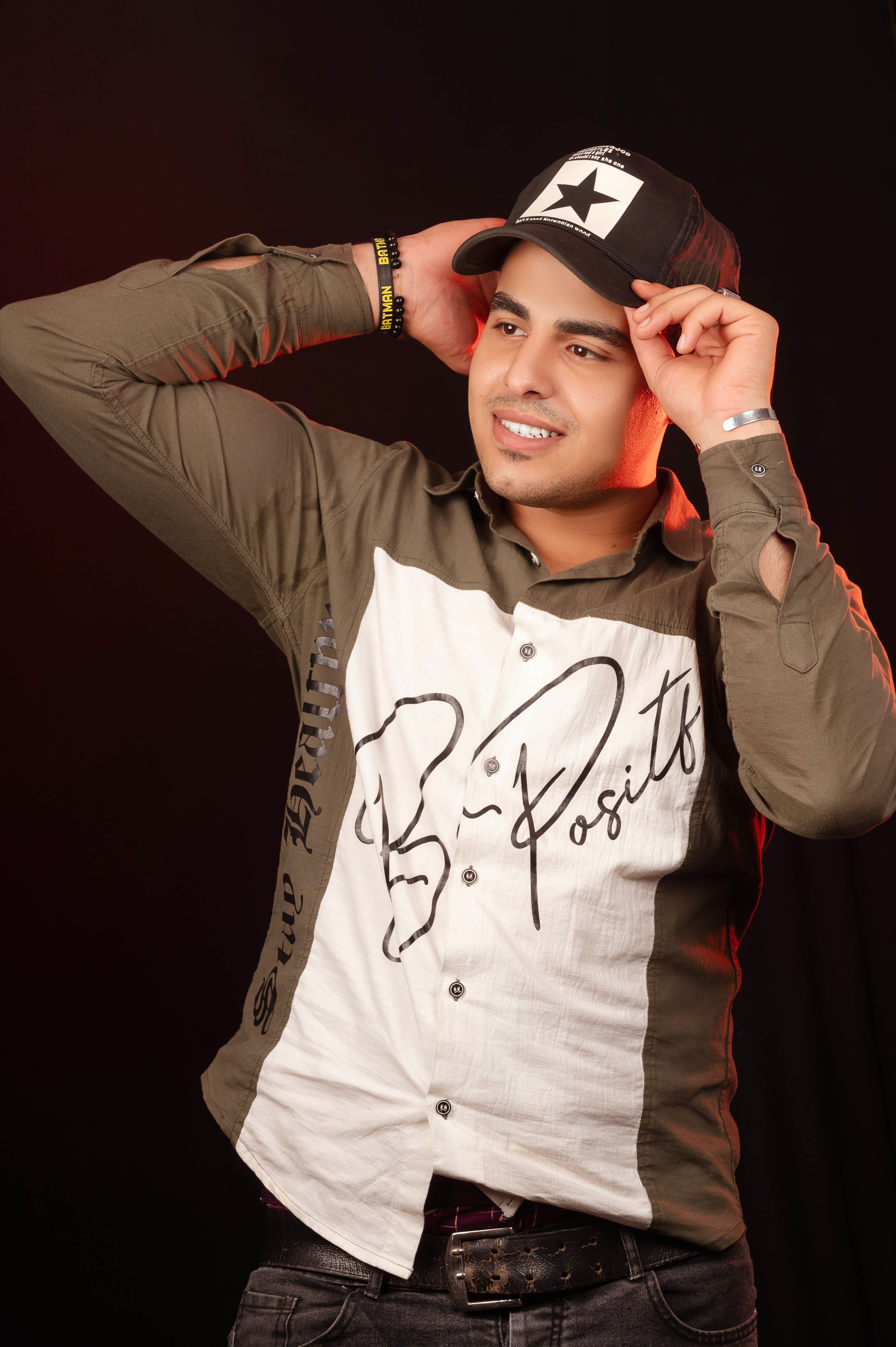 Portrait of a trendy young man wearing a cap and casual attire in a studio setting.