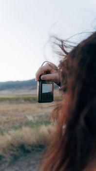 Close-up of a woman taking a photo outdoors with a mobile phone, showcasing nature.