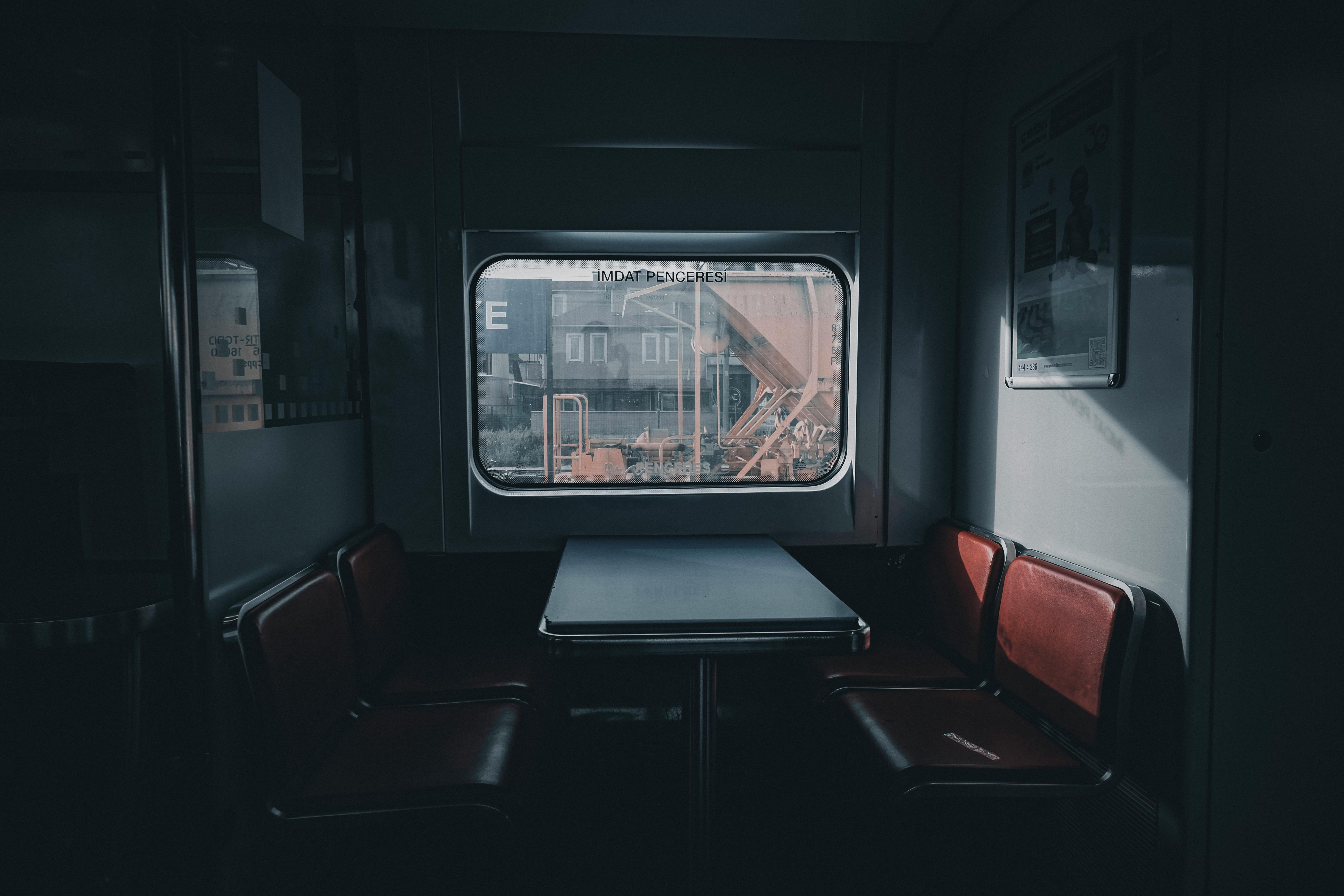 Quiet and empty train compartment with retro red seats around a table, captured indoors.
