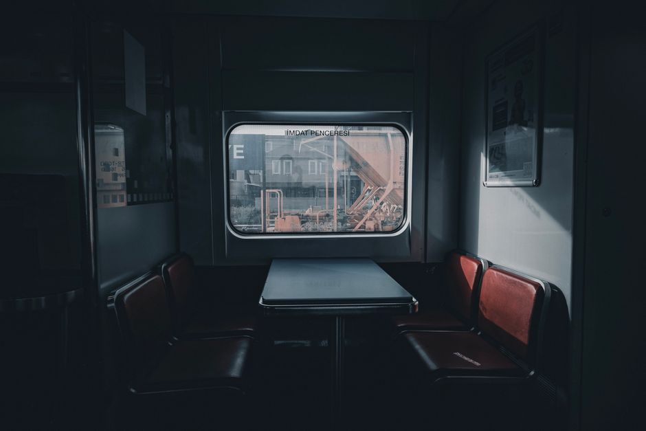 Quiet and empty train compartment with retro red seats around a table, captured indoors.