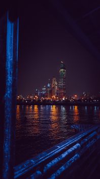 Vibrant city skyline at night reflecting on the water, showcasing modern urban architecture.