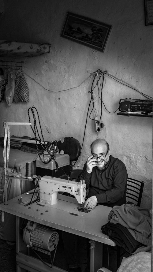 Free An experienced male tailor working on a sewing machine in a rustic workshop, focused on his craft. Stock Photo