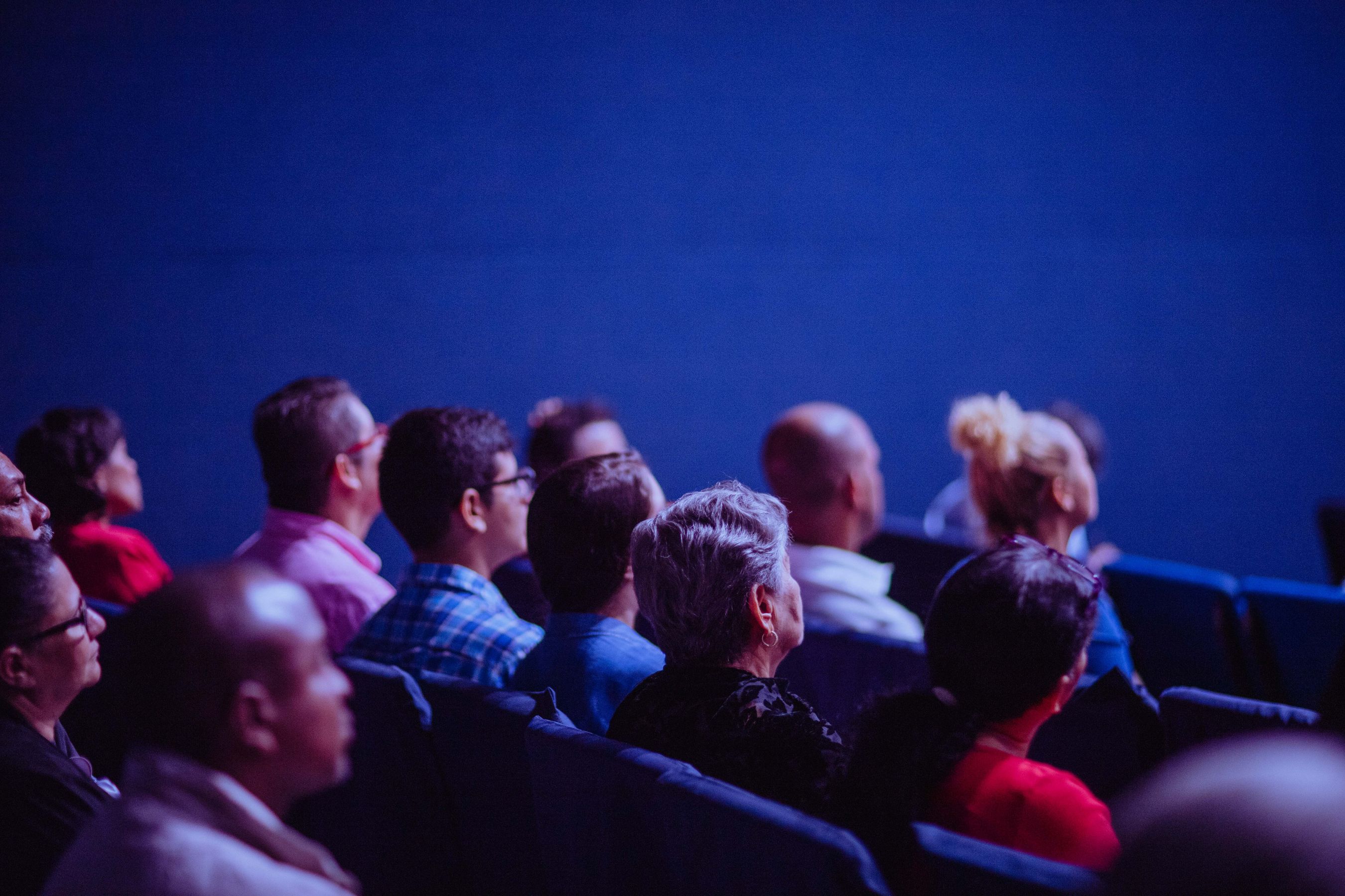 Large conference auditorium with professional stage lighting and live audience