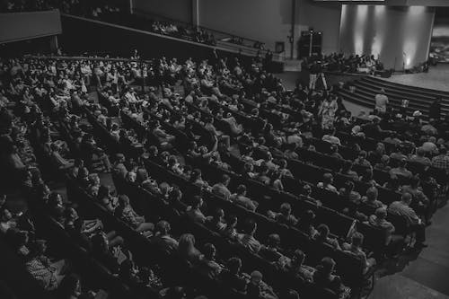 Free Grayscale Photography of People Sitting on Chair Inside Building Stock Photo