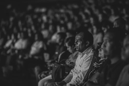 在拥挤的环境中，一位严肃的观众正全神贯注地观看一场单色表演