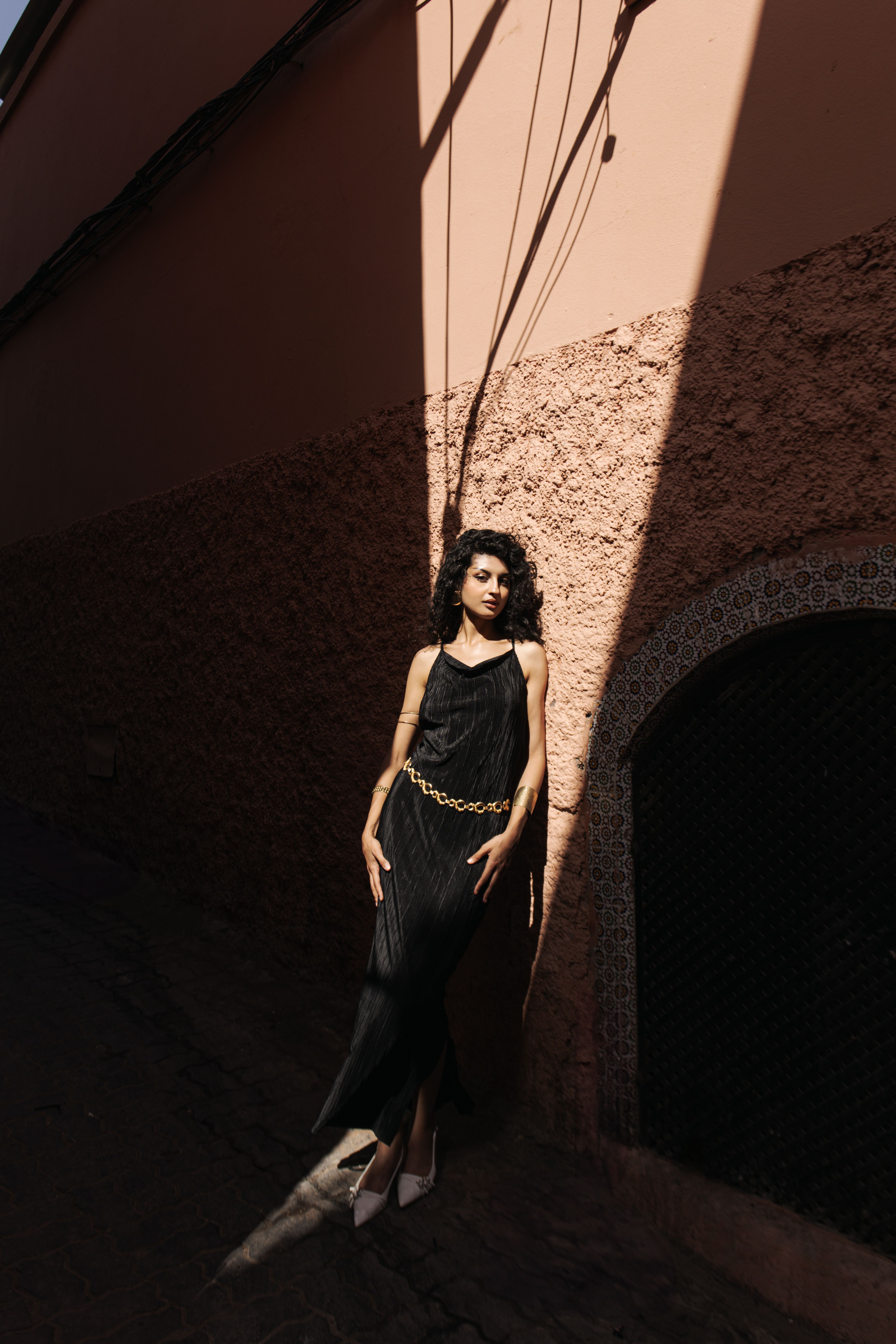 A woman in a black dress standing in front of a wall · Free Stock Photo