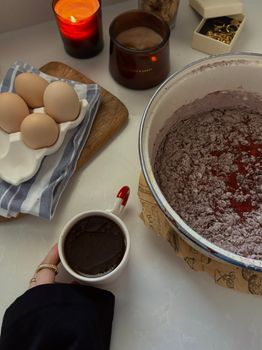 A baking scene with cocoa mixture, eggs, and a warm beverage, perfect for cozy indoor cooking.
