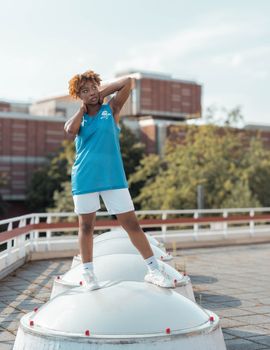 Stylish young woman poses outdoors on a sunny day in an urban environment, exuding confidence and fashion.