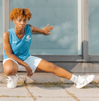 A young woman in athletic attire striking a pose against a modern building backdrop.
